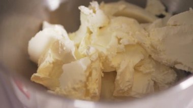 Pasta şefi kremalı peyniri gezegen mikserinin kasesine koyar.