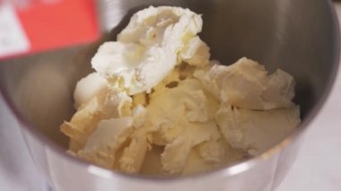 Yörünge mikserinin kasesinde duran beyaz kremin üzerine krema dökülür.