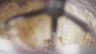 Kamera beyaz kremanın pasta için hazırlandığı bir kaseye bakıyor.