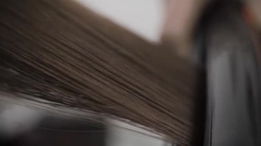 Bir buhar podunun yardımıyla kuaförde saç düzleştirme işlemi..