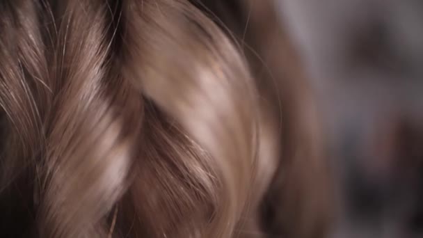 Very close-up, as the master puts the curled strands of hair to the blonde. — Stock Video