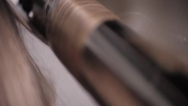 Very close-up of the curling iron for curling hair with blonde hair. — Stock Video