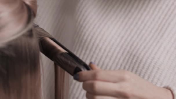 Close-up van de stylist voert een krul van licht haar. Golven in de kapsalon. — Stockvideo