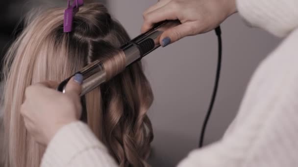 Close-up do estilista realiza um cachimbo de cabelo claro. Ondas no salão de beleza. — Vídeo de Stock