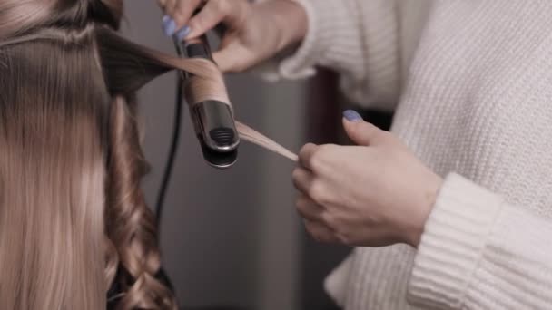 Il primo piano dello stilista effettua un ricciolo di capelli leggeri. Onde nel parrucchiere. — Video Stock