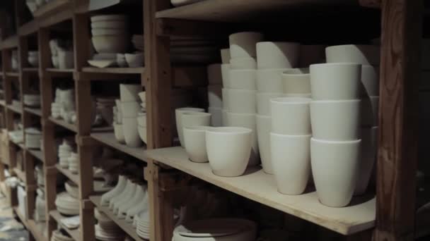 Canecas de cerâmica branca estão nas prateleiras na loja de produção — Vídeo de Stock