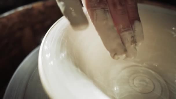 Close-up af en menneskelig hånd male en plade med hvid maling på en pottemagere hjul. – Stock-video