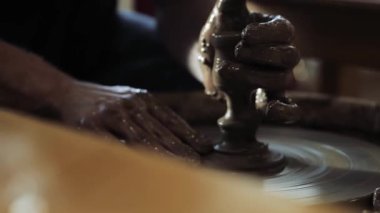 Çömlekçilerin elleri balçığa bulanmış, çömlekçilerin çarkında küçük bir bardak oluşturuyorlar.