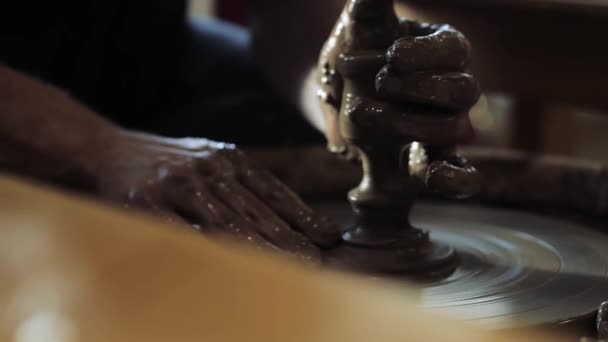 De pottenbakkers handen gekleurd in klei, het creëren van een klein glas op het pottenbakkerswiel — Stockvideo