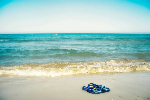 Chinelos na praia perto do mar azul — Fotografia de Stock