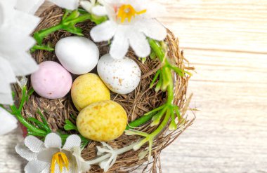 Çiçeklerle çevrili bir yuvada paskalya yumurtaları.