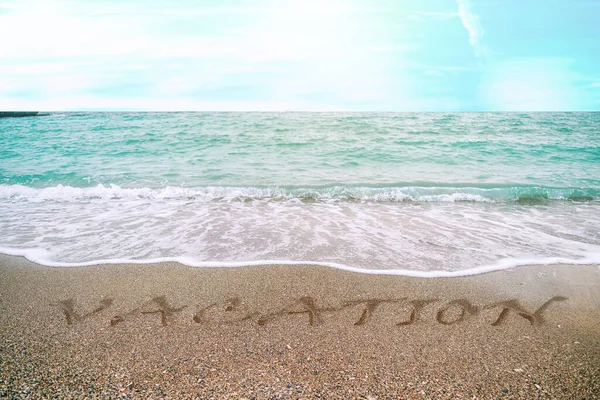 Dovolená napsaná v písku na pláži — Stock fotografie