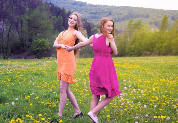 2 つの可愛い女の子が花畑の上で踊って — ストック写真