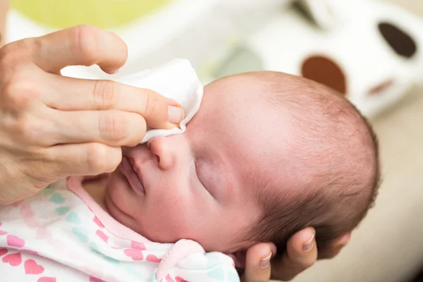 Madre limpiando los ojos de un bebé recién nacido — Foto de Stock