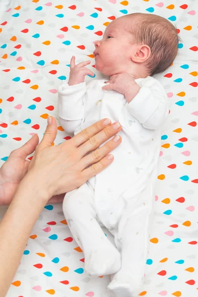 Novorozené dítě oblečený v bílém položení na zádech, s colics — Stock fotografie