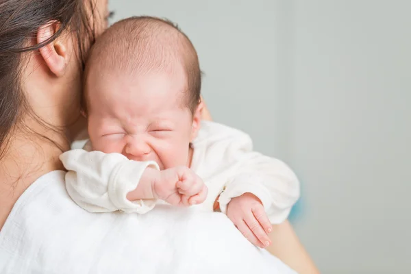 Neugeborenes schreit vor Schmerzen mit Kolik auf den Schultern der Mutter — Stockfoto