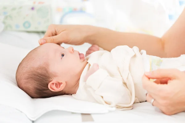 Mother caressing her female newborn baby daughter while changing her clothes — Stock Photo, Image