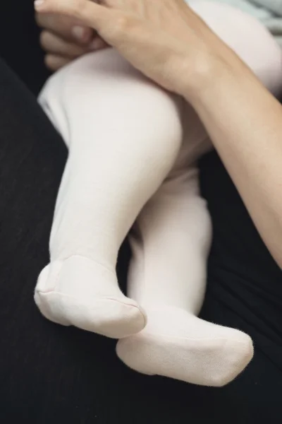 Babybeine in kleinen Strümpfen auf dem Schoß ihrer Mutter — Stockfoto