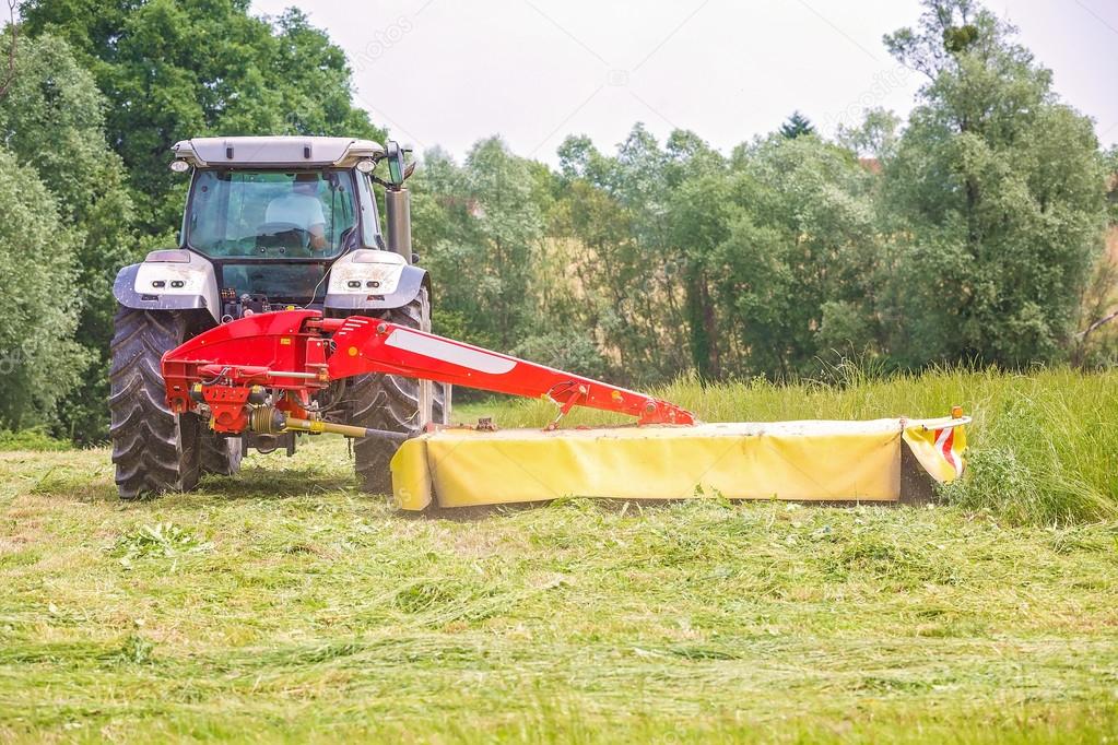 Farmer driving a tractor on the field with the attached tool