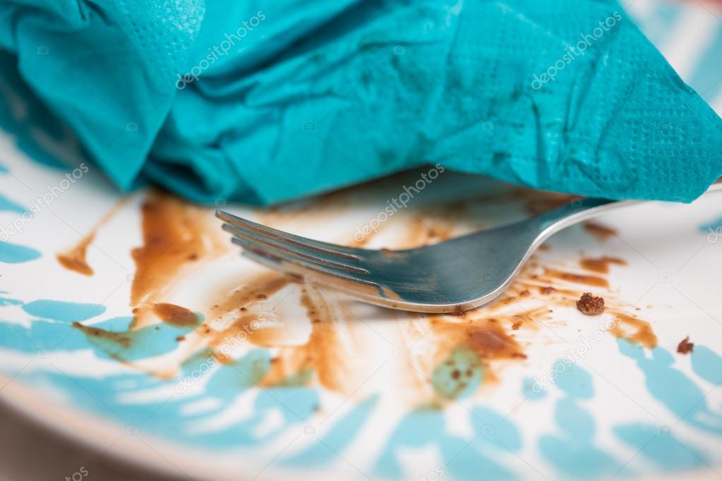 Cake crumbs leftovers on the blue plate with fork and torn used 