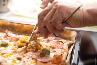 Adam'ın bir bıçak ile kesme dilim ev yapımı pizza eller; Pizza