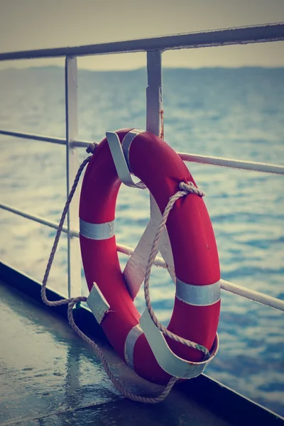 Plastic orange saving belt by the railing fence of the ferry — Stock Photo, Image