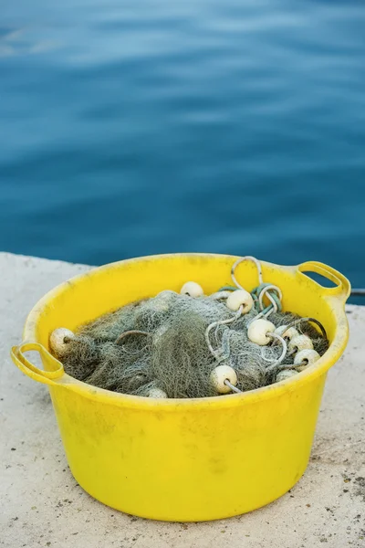Gray fishing net on the heap in the yellow plastic container — Stock Photo, Image