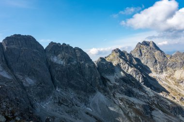 Şaşırtıcı kayalık dağ sırtı beyaz bulutlar ile mavi gökyüzü altında