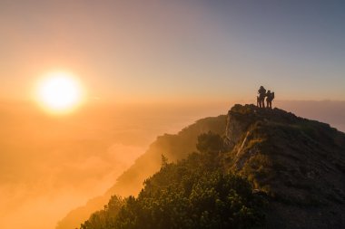 Tourists watching the sunrise at the top of the mountain clipart
