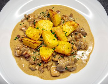 Mantarlı, etli ve kızarmış patatesli güzel bir tabak kremalı sos..