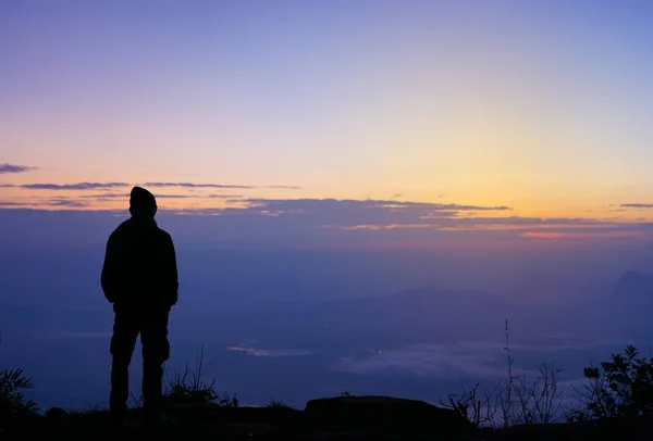 Selective focus of men\'s silhouette alone looking at the sunrise nature view with beautiful color background