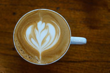 Gözde bir sabah kahvesi kapuçinosuna odaklanın. Beyaz bir fincanda lale şeklindeki süt köpüğü ile süslenmiş.                      