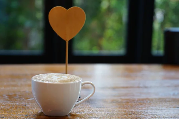 Selective focus at a favorite morning coffee cappuccino decorated with a beautiful tulip-shaped milk foam art in a white cup and  heart symbolize Valentine\'s Day