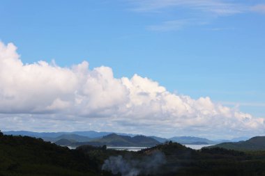 Dağların ve denizin üzerindeki bulutlu mavi gökyüzü