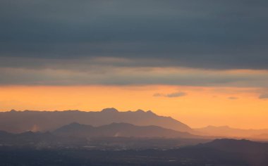 Gökyüzü bulutlu ve kışın dağların üzerinde gün batımı
