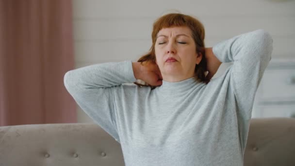 Žena středního věku trpí bolestí šíje, starší dáma masíruje krční svaly — Stock video