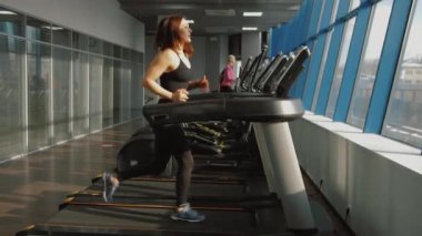 Spor salonunda koşu bandında koşan kadın, kardiyo eğitimi alıyor.