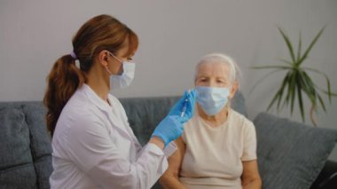 Tıp hemşiresi yaşlı kadına koronavirüs aşısı yapıyor.