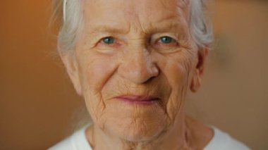 Kameraya bakan yaşlı güzel bir kadının portresi. Yaşlı kadın mutlu ve gülümsüyor.