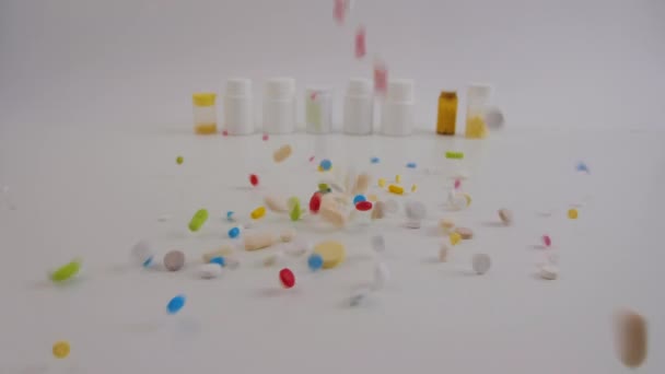 Diverse pillole colorate che cadono sul tavolo con lattine di compresse, farmaci e farmacie — Video Stock