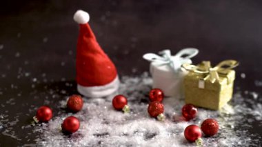 Kırmızı küçük toplar Noel ağacı için karla kaplı bir masanın üzerine yuvarlanır. Karanlık bir arkaplan hediyesi.