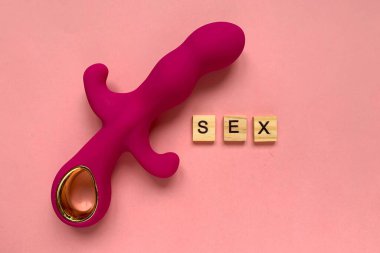 Seks oyuncağı. Pembe arka planda pembe vibratör. Yetişkin için kullanışlı