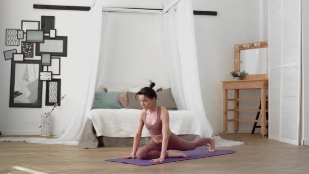 Mujer caucásica en ropa deportiva realiza yoga asanas eka pada rajakapotasana — Vídeo de stock