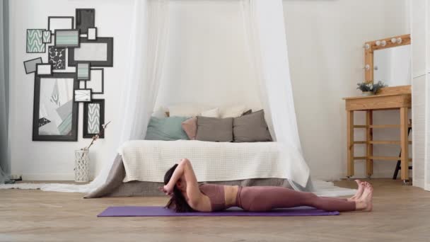 Mujer caucásica en ropa deportiva realiza yoga Fish Pose, Matsyasana — Vídeo de stock