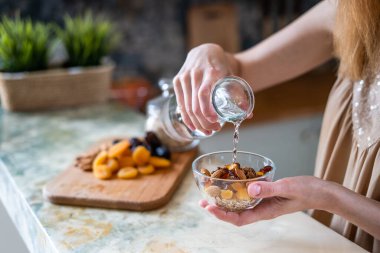 Mutfakta kadın cam kasede ev yapımı müsli hazırlıyor.