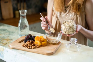 Mutfakta kadın cam kasede ev yapımı müsli hazırlıyor.