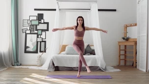 Mujer caucásica en ropa deportiva realiza yoga garudasana, pose de águila — Vídeos de Stock