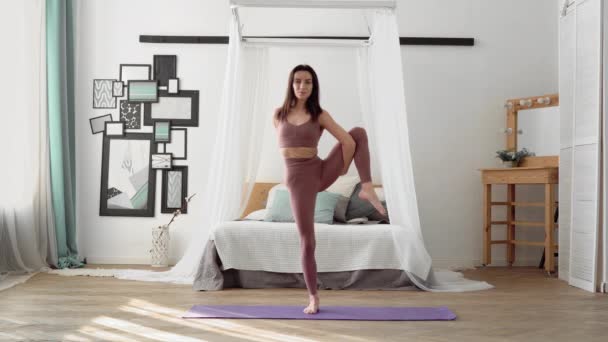 Femme caucasienne en vêtements de sport effectue yoga roi danseuse pose, natarajasana — Video