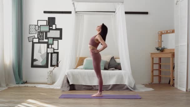 Mujer caucásica en ropa deportiva realiza yoga estiramiento calentamiento — Vídeos de Stock