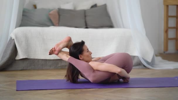 Kaukasierin in Sportkleidung führt Yoga Yoganidrasana, Yogische Schlafhaltung, vor — Stockvideo
